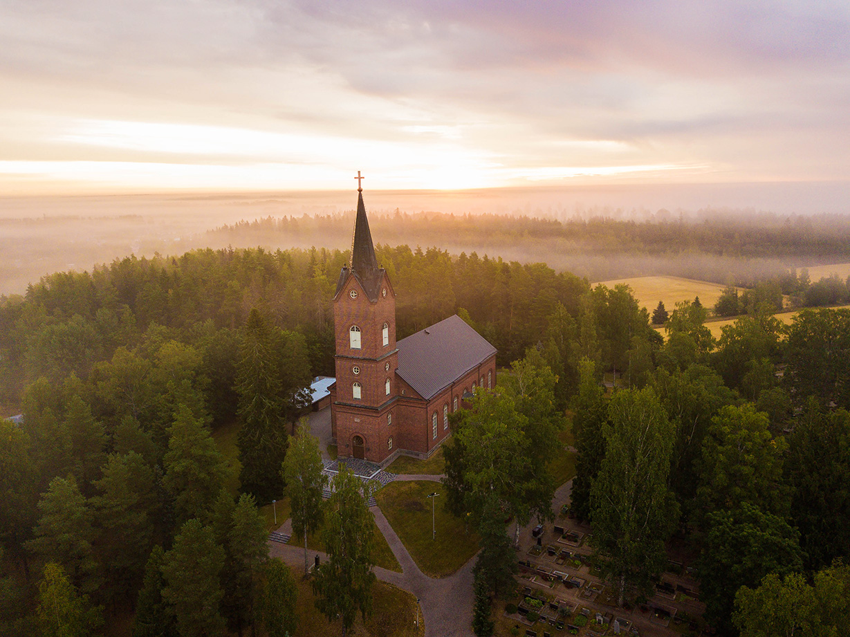 Mäntsälän punaruskeatiilinen kirkko ylhäältäpäin kuvattuna.