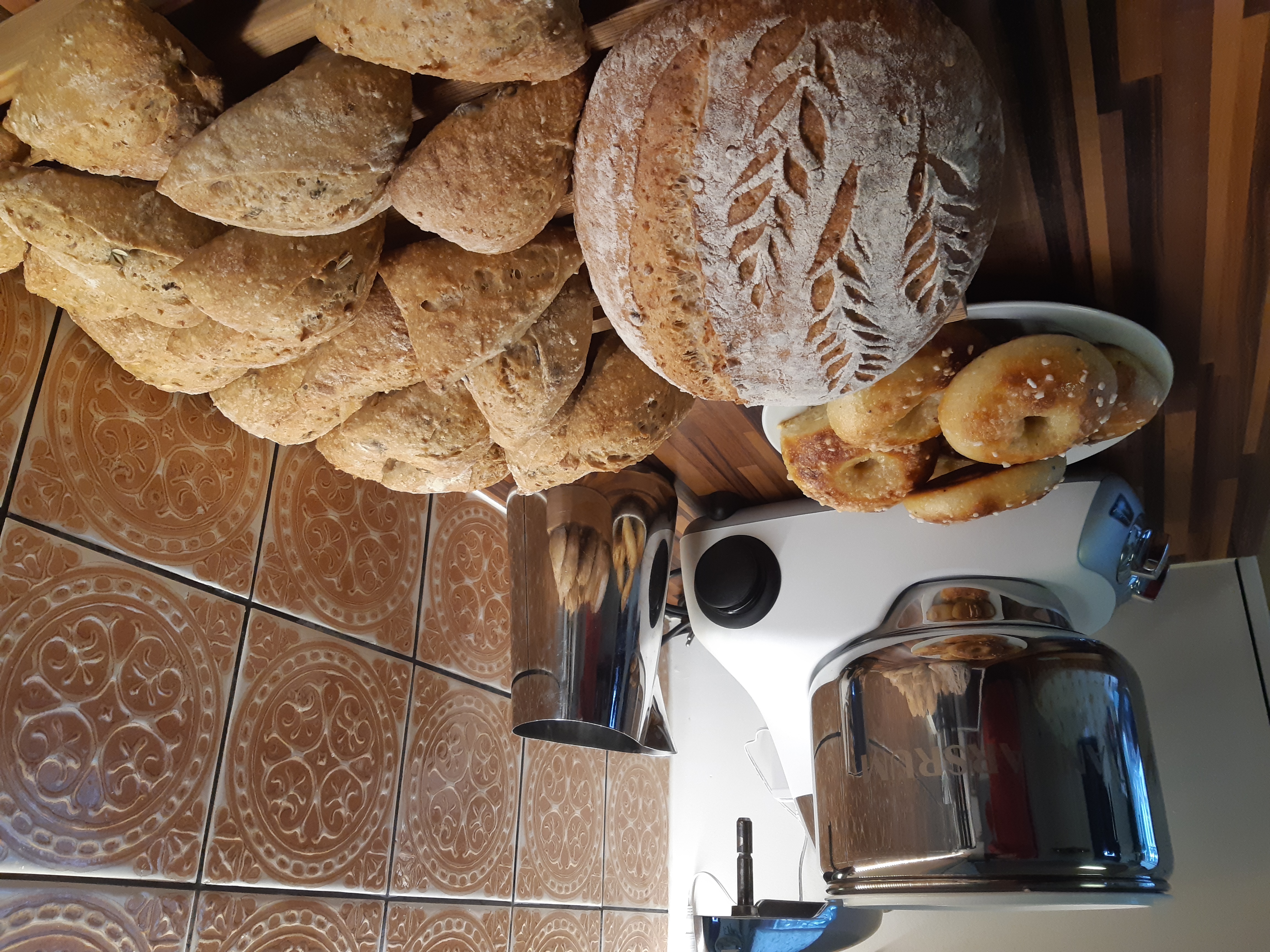 Taustalla on leipäkone, jonka edessä on tuoretta leipää ja pullaa.