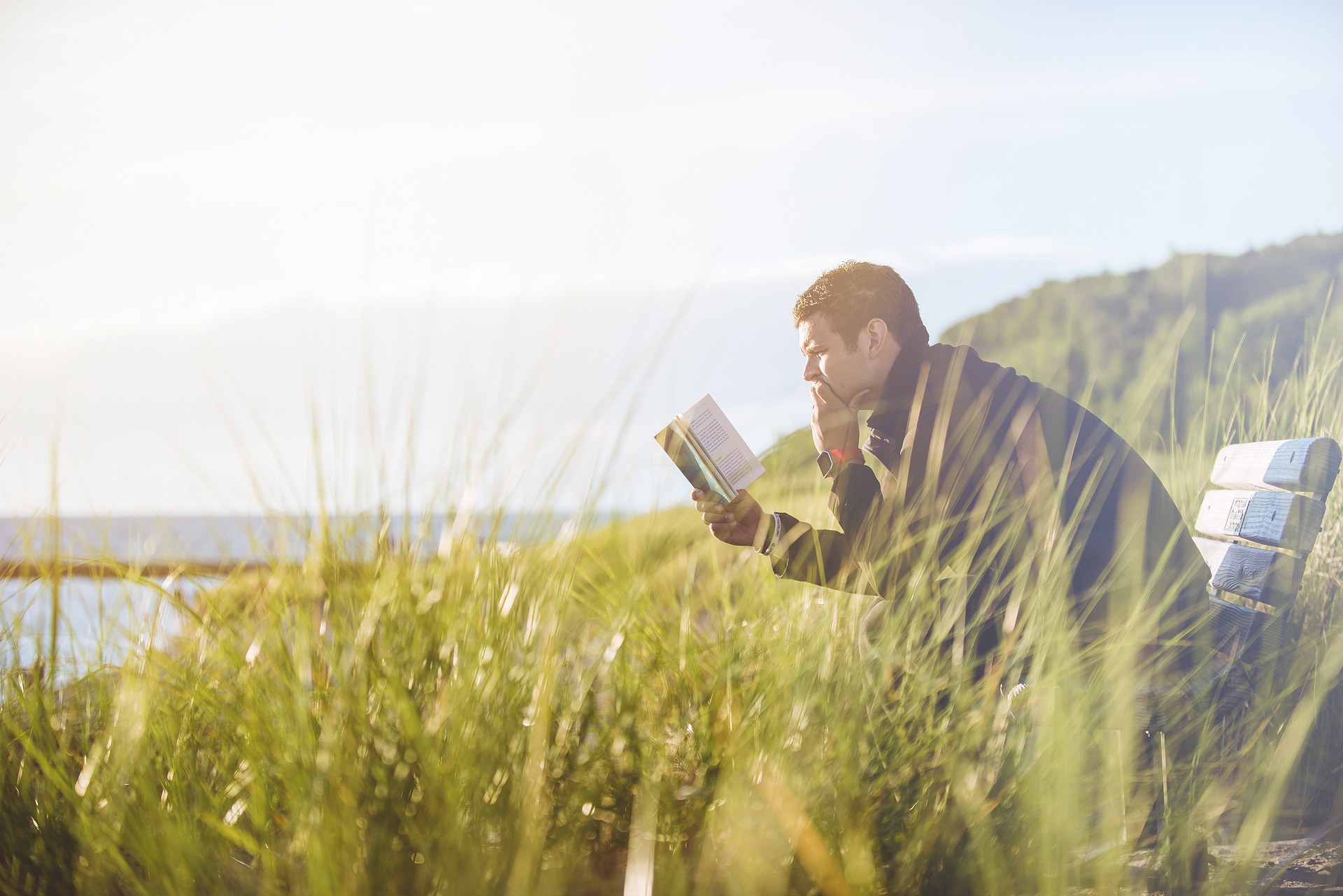 Mies lukee niityllä