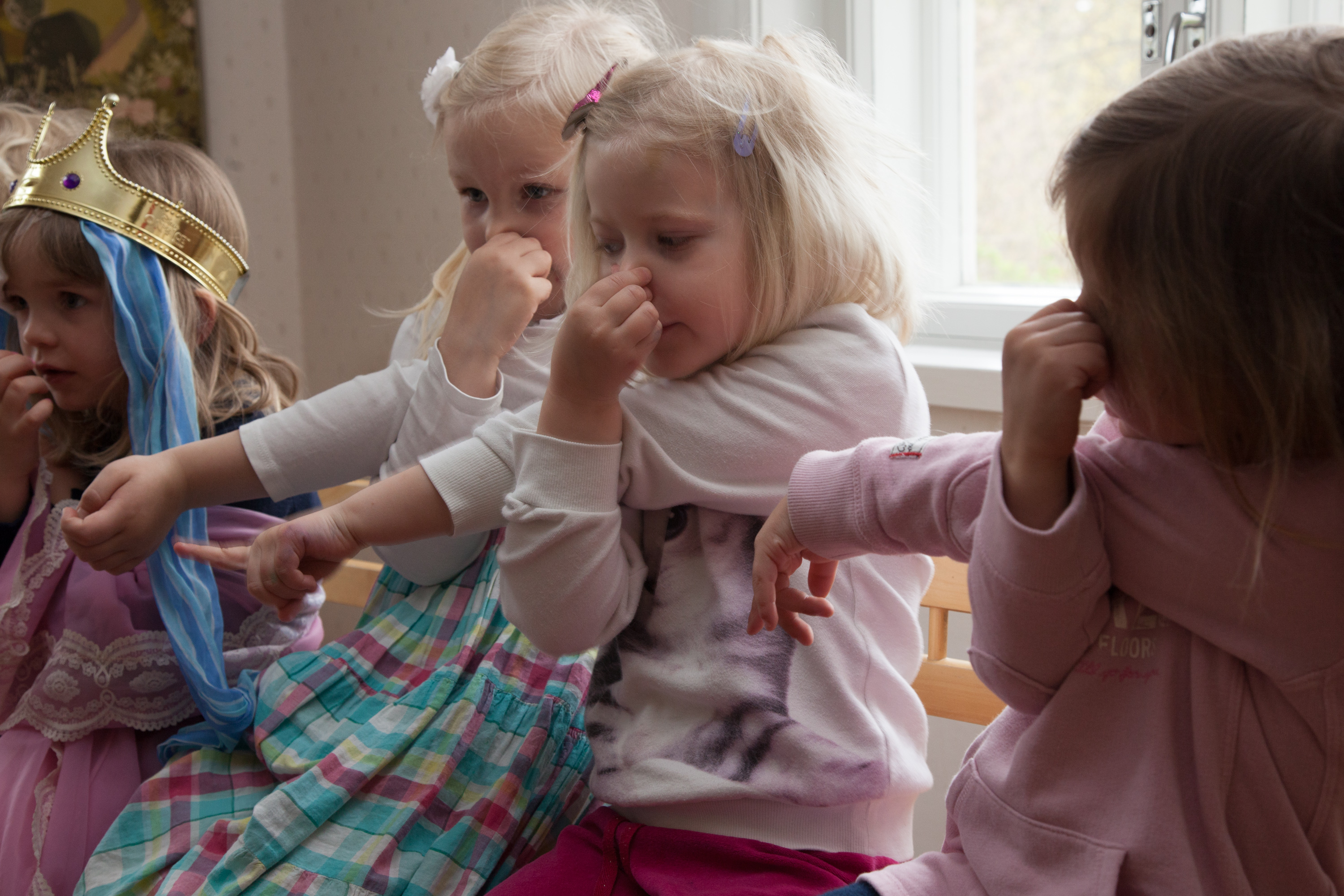Lapset leikkivät ja pitävät sormella nenästään kiinni.