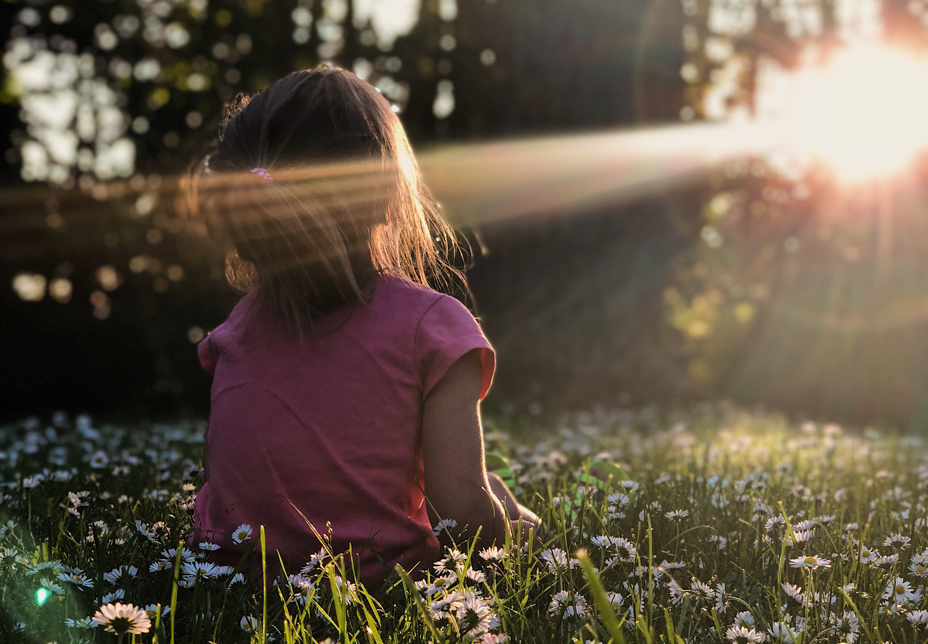 Lapsi istuu niityllä kasvot aurinkoon.