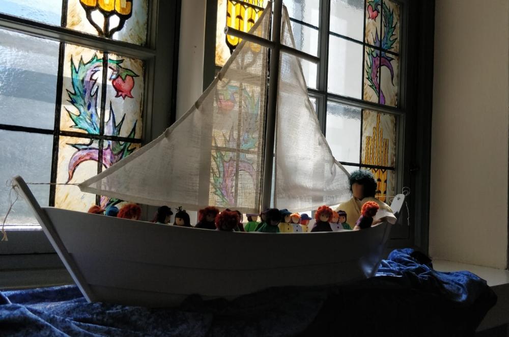 Käsintehty Jeesuksen ajan vene, jossa purje. Veneessä huovutettuina hahmoina Jeesus ja ihmisiä.